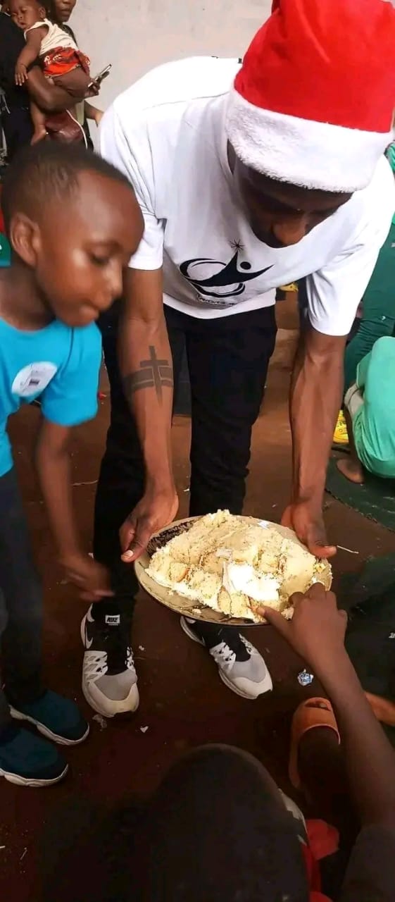 A volunteer in a Santa hat sharing a meal with children at the 2024 Christmas outreach
