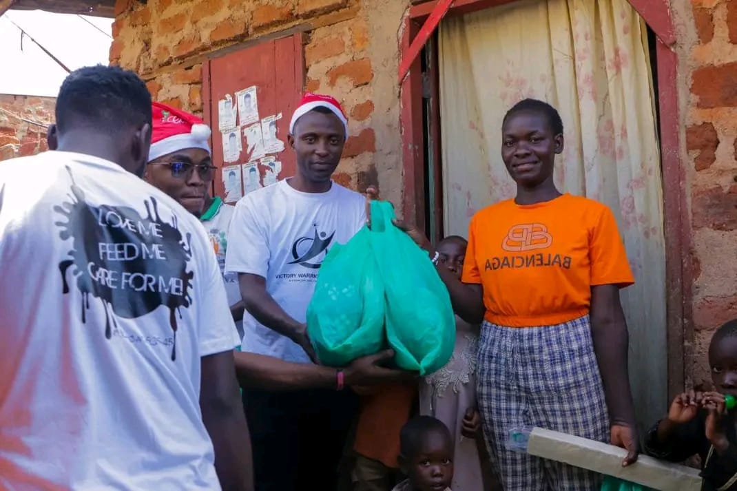 A volunteer handing a green Christmas hamper to a family outside their home
