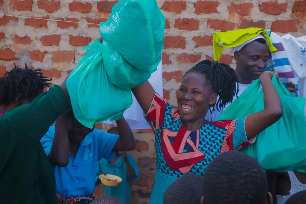 A woman joyfully carrying a Christmas hamper after receiving it