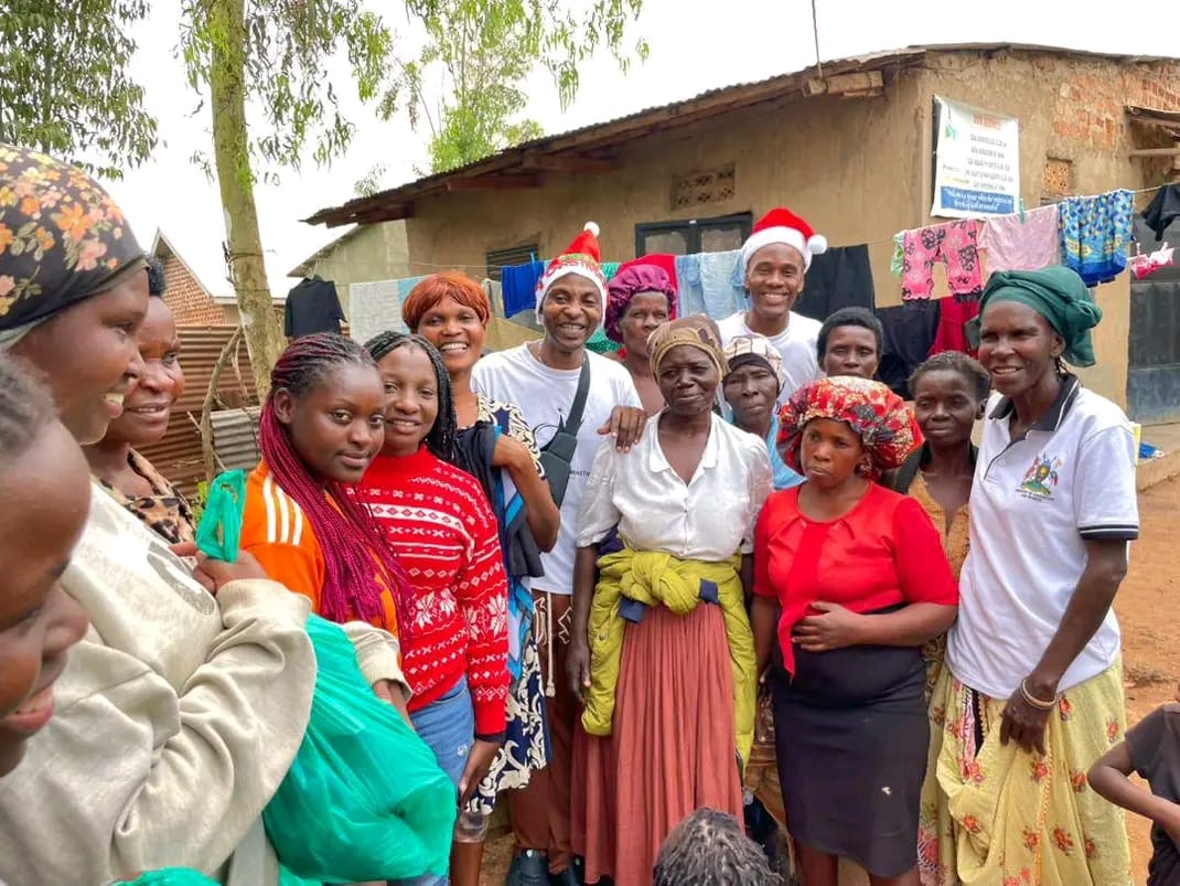 Volunteers in Santa hats posing with families after distributing Christmas gifts