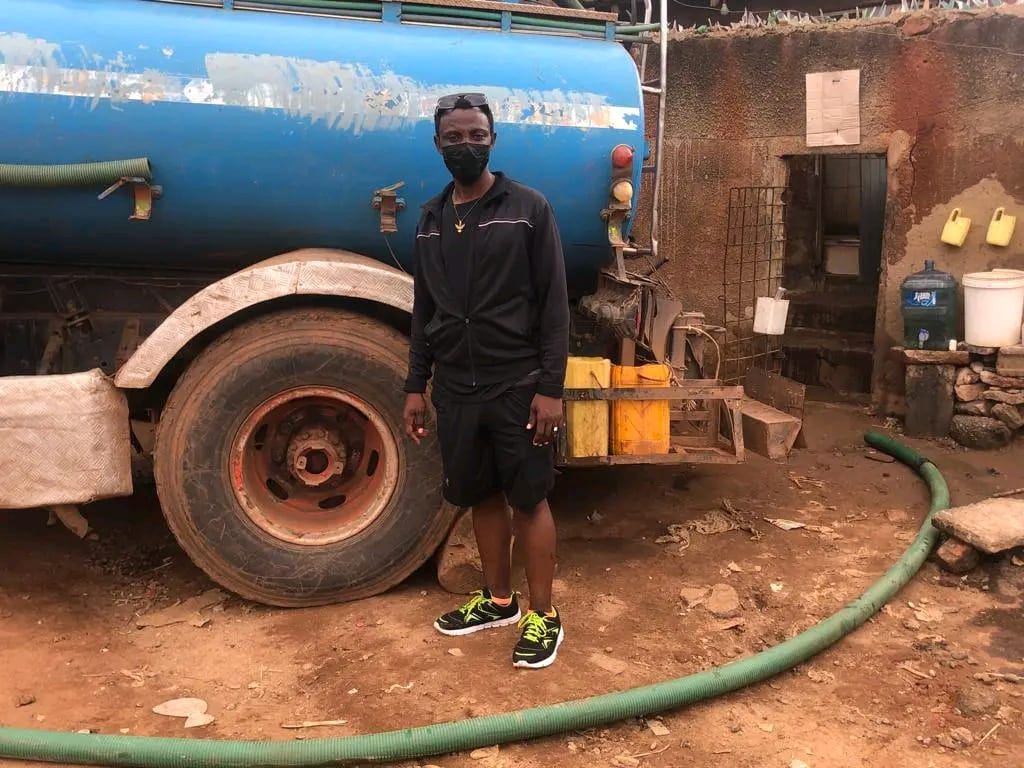A volunteer standing in front of a sanitation truck during the emptying of a community latrine