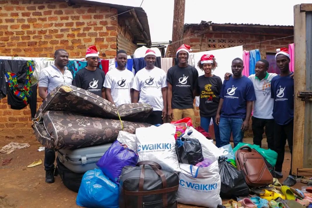 Kuganja Foundation volunteers standing with collected donations of clothes, bedding and bags
